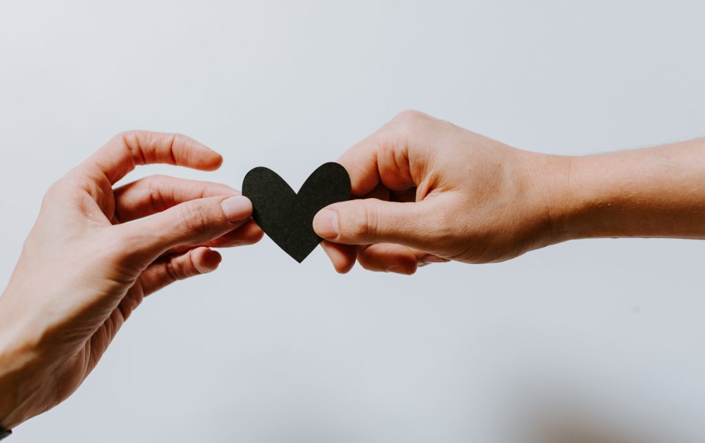 Two hands hold onto a black heart shaped object