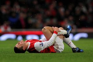A footballer on the ground in pain holding his shin
