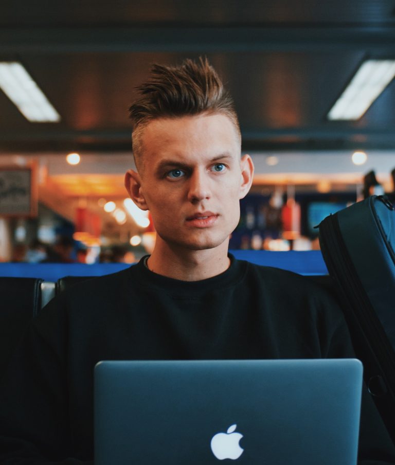 A man looking towards the camera with a blue laptop in his lap.