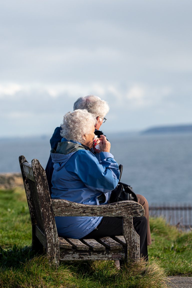 Two elderly individuals look towards the sea