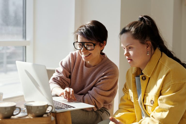 Two women look on a laptop towards the left of the image,