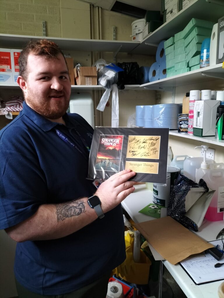 An individual excitedly holds up a stranger things plaque